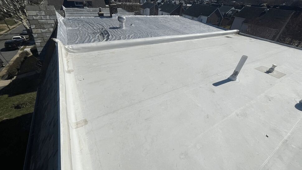 Aerial view of a white flat roof membrane with vents and perimeter flashing.