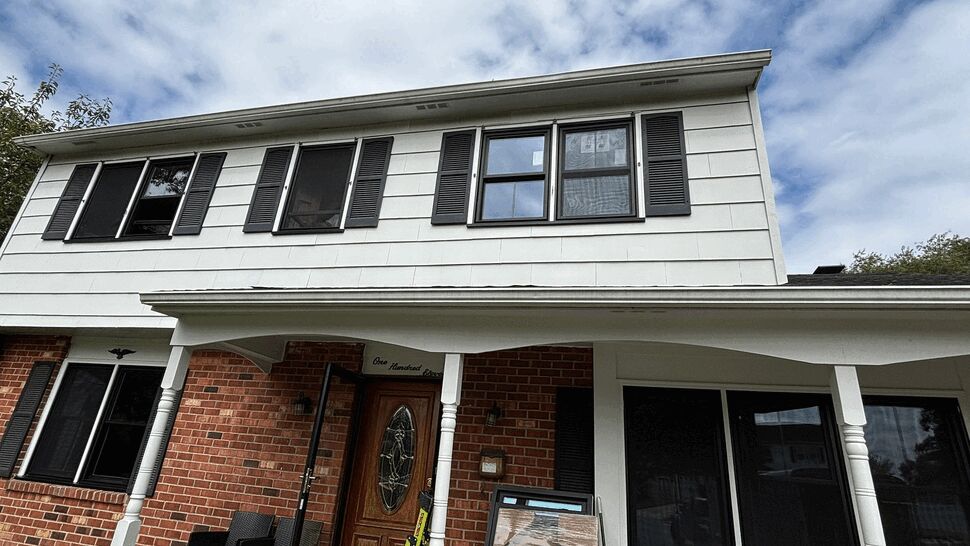 Front Home Window Installation | Tycos Roofing And Siding Inc Home exterior with newly installed black-framed windows and shutters.