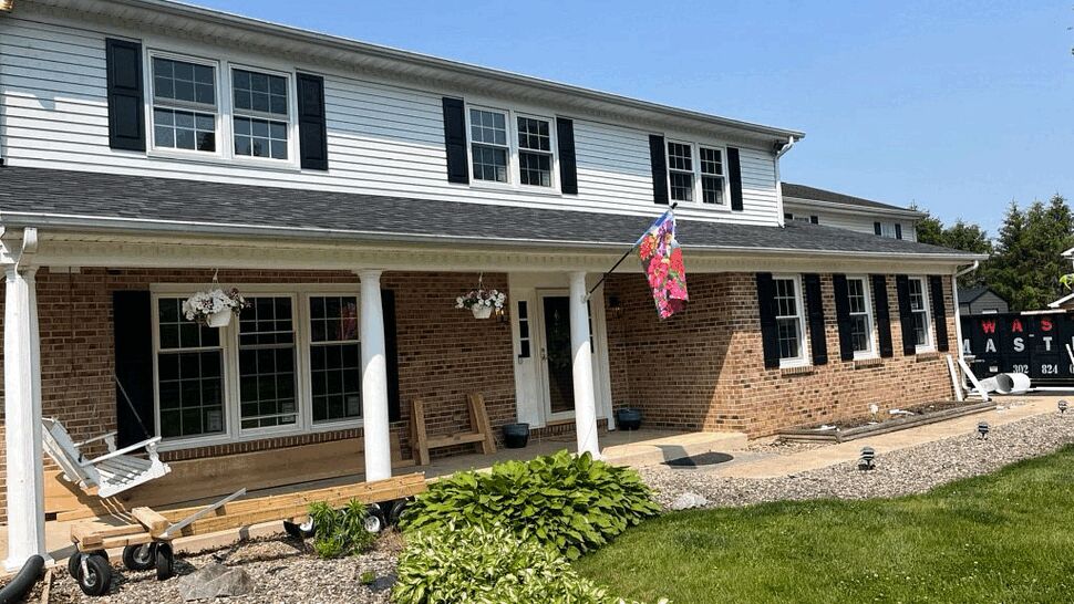 Front Porch Roof with New Gutters | Tycos Roofing And Siding Inc Two-story brick and siding home with covered porch, visible roofline and white gutters