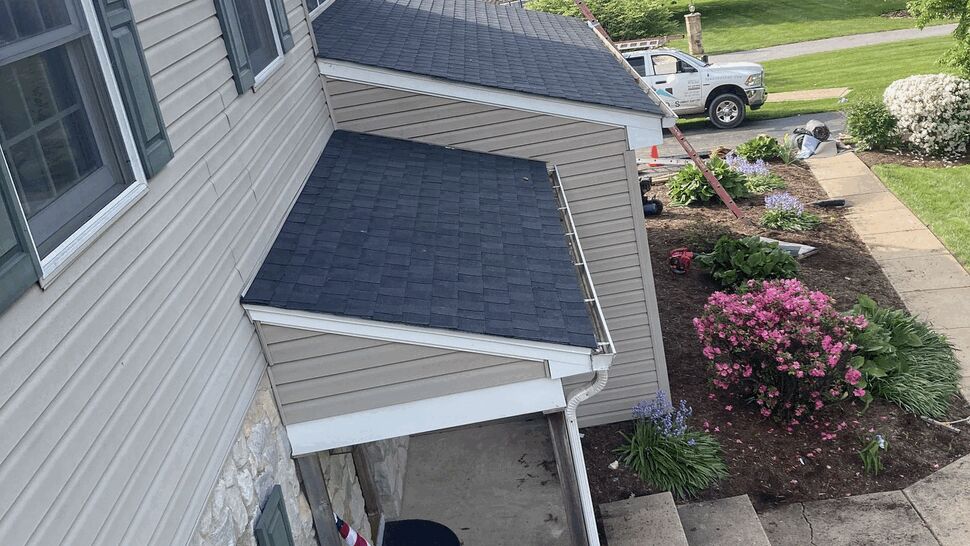 Aerial view of front porch roof, siding, windows and gutters with landscaping