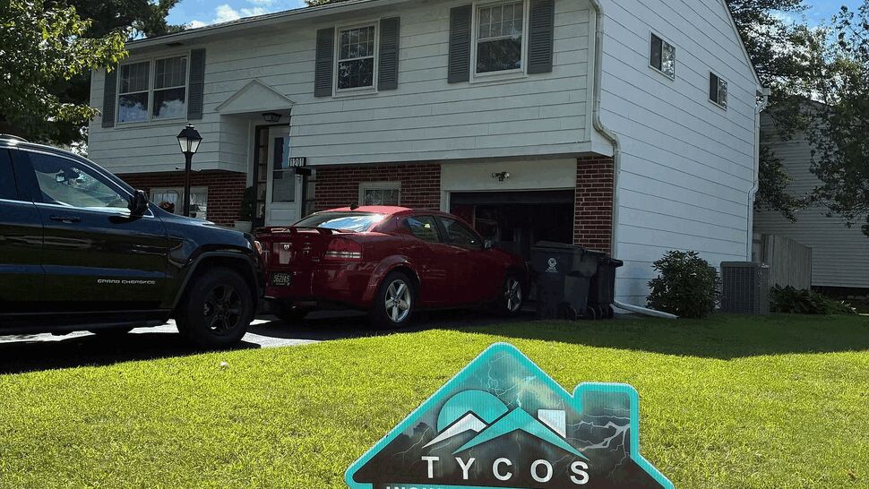 Yard sign at residential property | Tycos Roofing And Siding Inc Tycos yard sign on front lawn of a split-level house advertising roofing services.