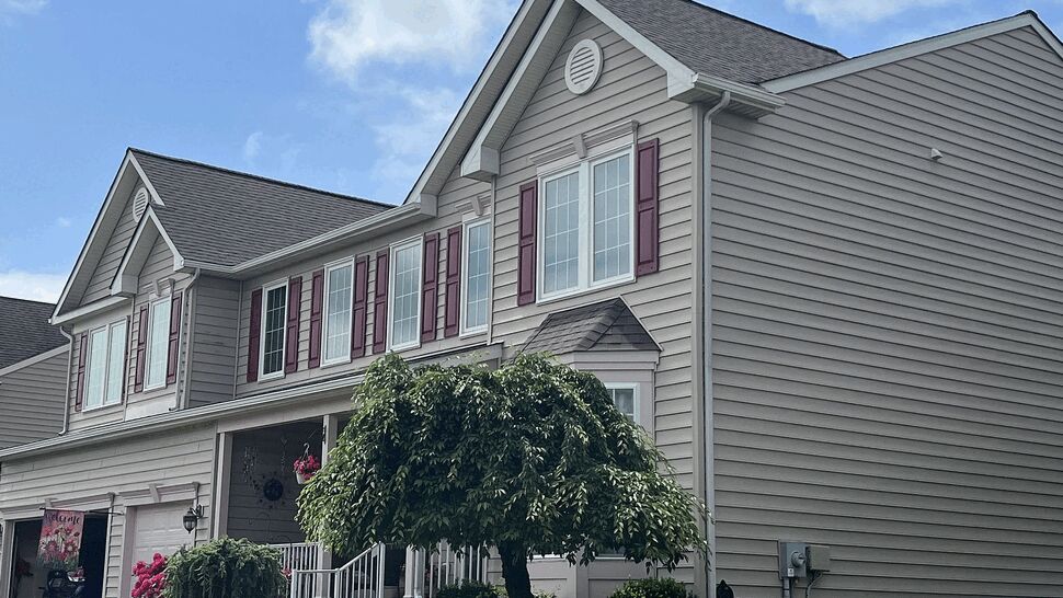Side angle showing gable roof, shingles, and beige vinyl siding