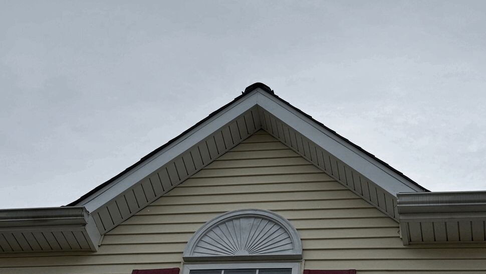 Gable Window and Siding | Tycos Roofing And Siding Inc Gabled home exterior with cream siding, arched window, red shutters, and roofline