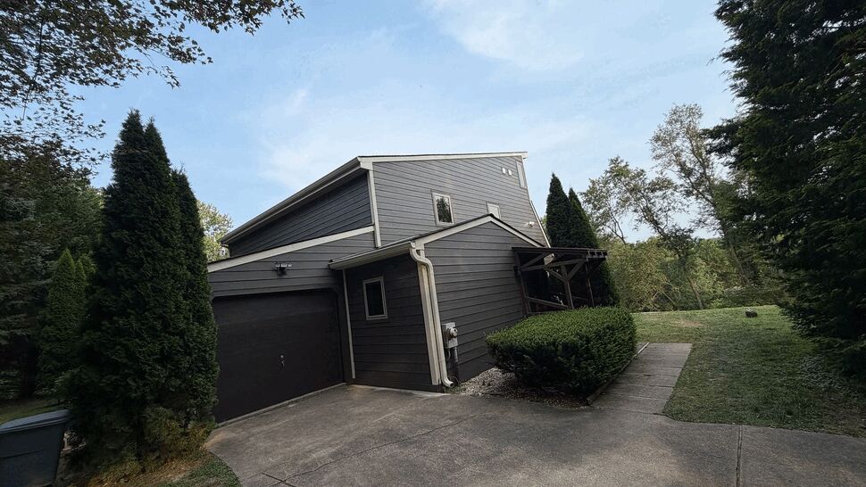 Garage Gutters and Downspouts | Tycos Roofing And Siding Inc Garage side with dark door, white gutters and downspout next to driveway.