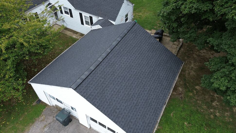 Top-down view of a large garage shingle roof and adjacent yard.