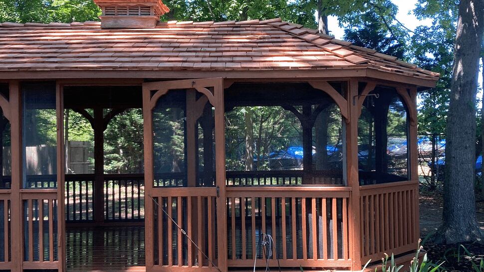 Gazebo entrance with steps and screens | Tycos Roofing And Siding Inc Front entrance of a wooden gazebo with steps, railing, and screened openings.