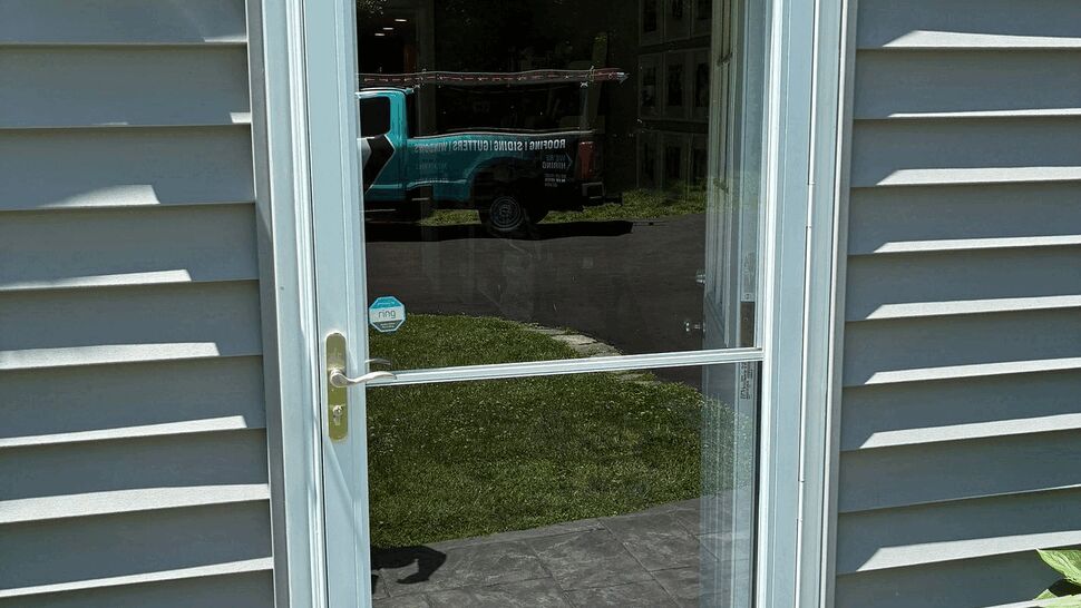 Glass storm door with white frame and brass handle on exterior