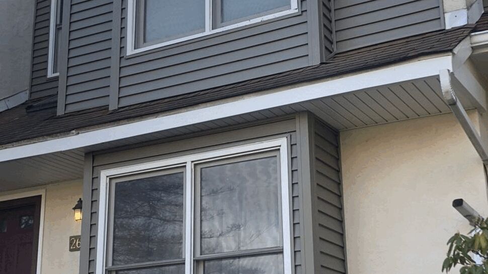 Gray vinyl bay window and matching siding on a townhouse exterior.