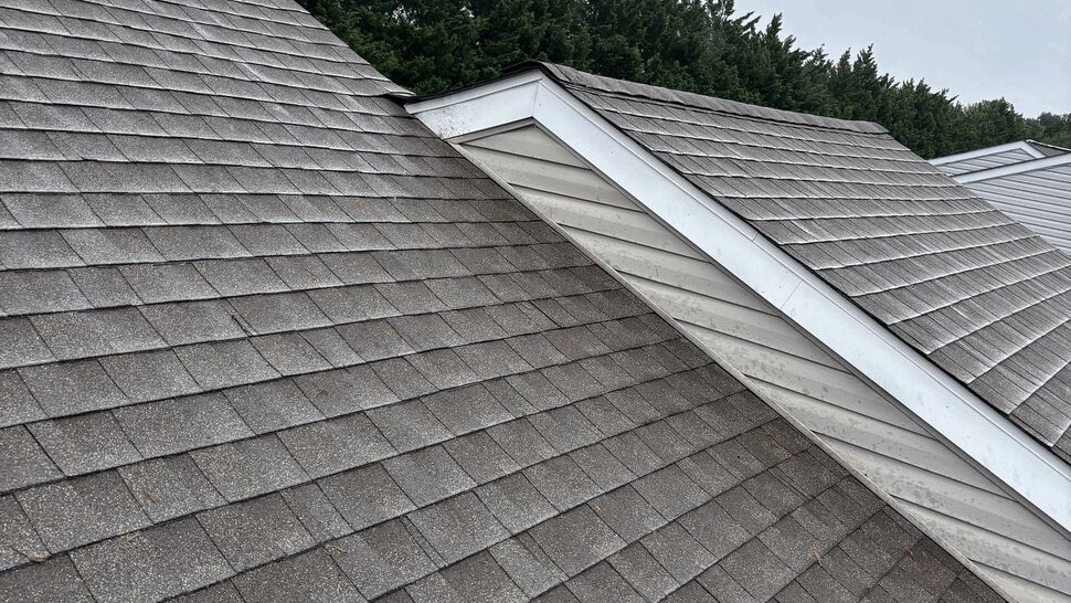 Gray asphalt shingle roof with intersecting gables and white trim