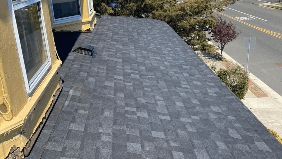 New gray asphalt shingle roof on a lower roof section overlooking the street