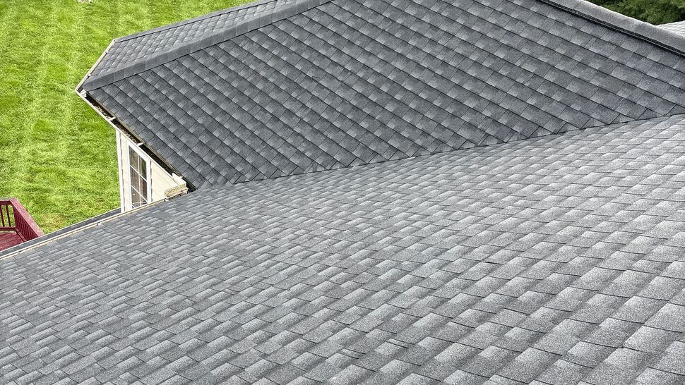 Aerial view of a grey asphalt shingle roof over a green backyard
