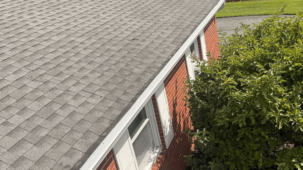 Grey shingle roof and gutters | Tycos Roofing And Siding Inc Top-down view of grey shingle roof and white gutter on brick house