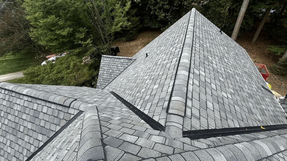 Aerial close-up of grey shingle roof intersection with ridges and valleys
