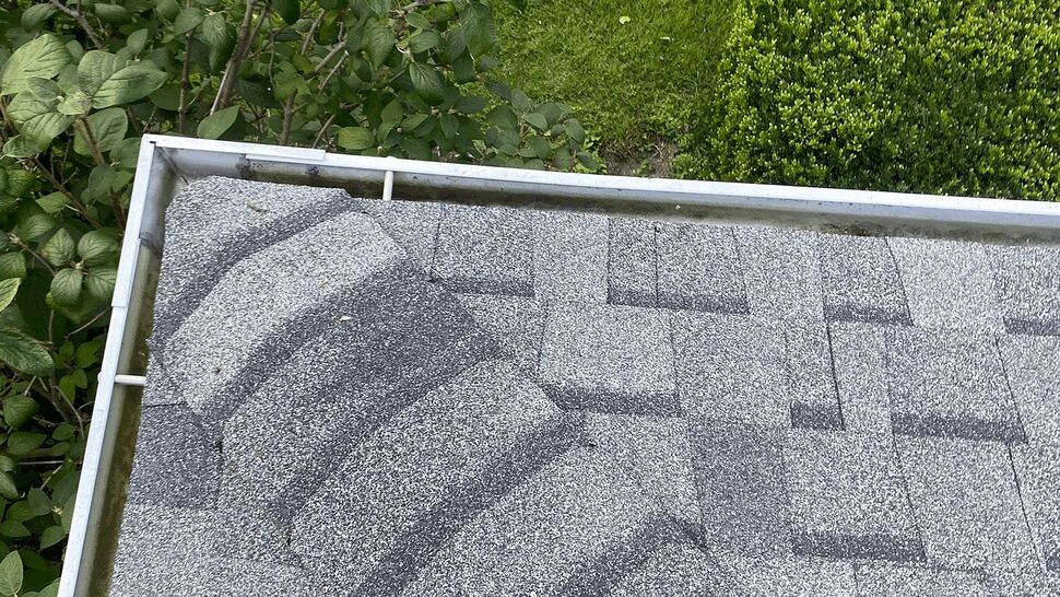 Shingle and Gutter Close-up | Tycos Roofing And Siding Inc Close-up of gray asphalt shingles and adjacent metal gutter