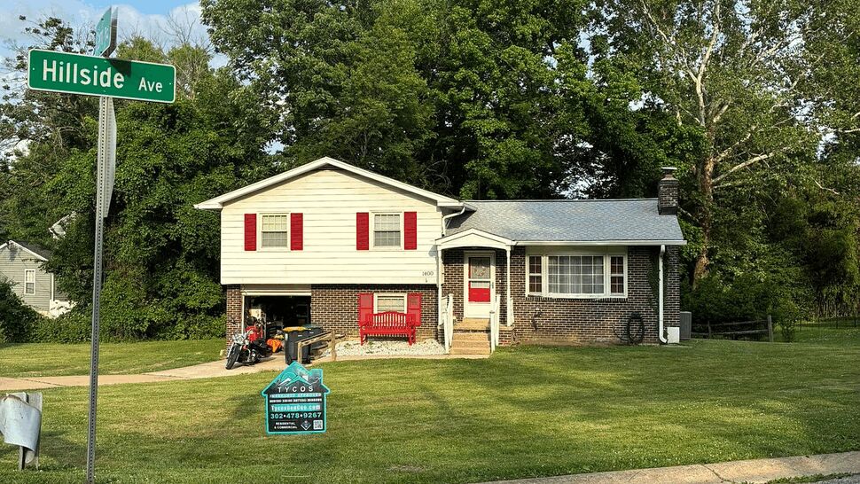 Split-level home with Tycos Roofing yard sign on the front lawn