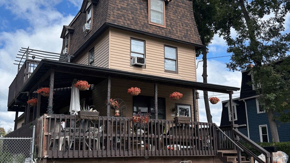 Three-story house with mansard roof, wrap porch, and front deck