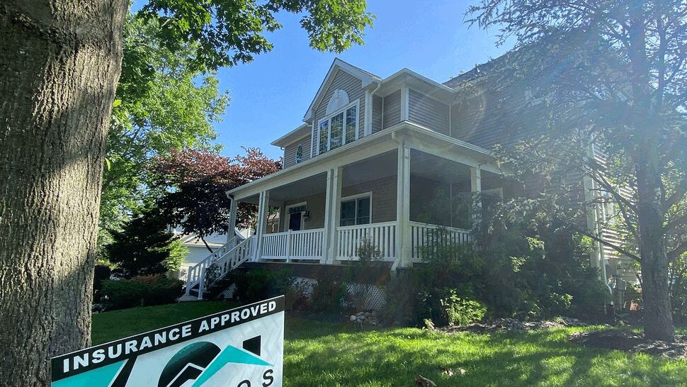 Front yard sign for Tycos in front of a two-story house with a covered porch.