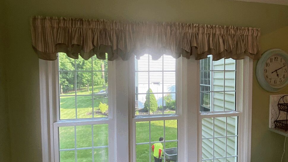 Interior view through three-pane bay windows looking onto a green lawn.
