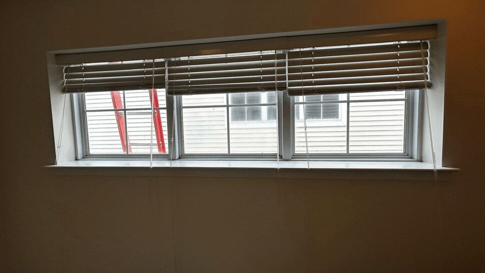 Three-Panel Interior Window | Tycos Roofing And Siding Inc Interior three-panel window with blinds and exterior ladder visible