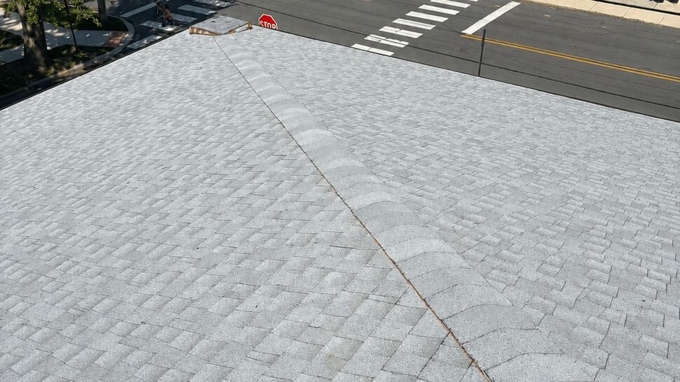 Close-up of a light-gray shingle roof ridge overlooking an intersection.