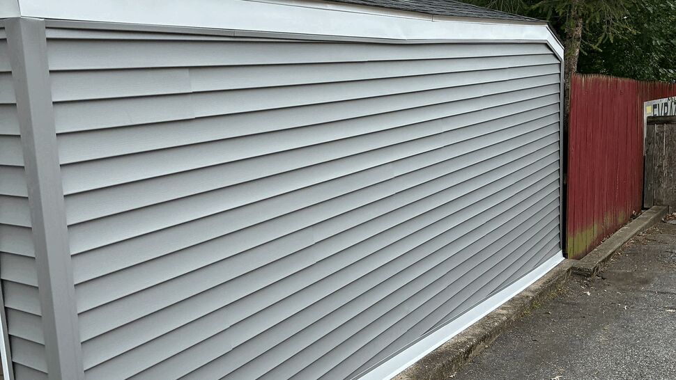 Long gray vinyl siding wall along driveway with neat trim
