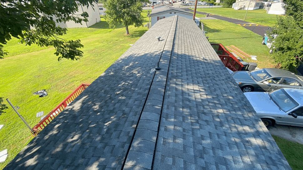 Aerial view down the length of a gray asphalt shingle roof with a continuous ridge vent.