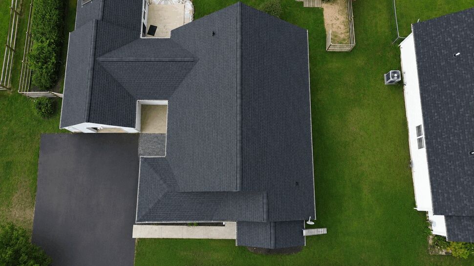 Top-down drone shot of the full roof layout and adjacent driveway.