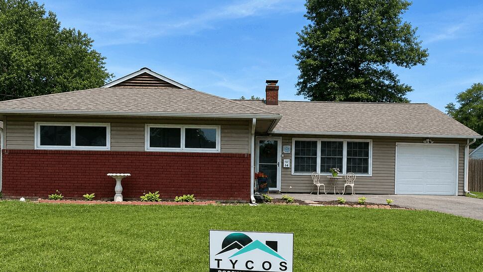 Single-story ranch home with Tycos sign on green lawn and new roof