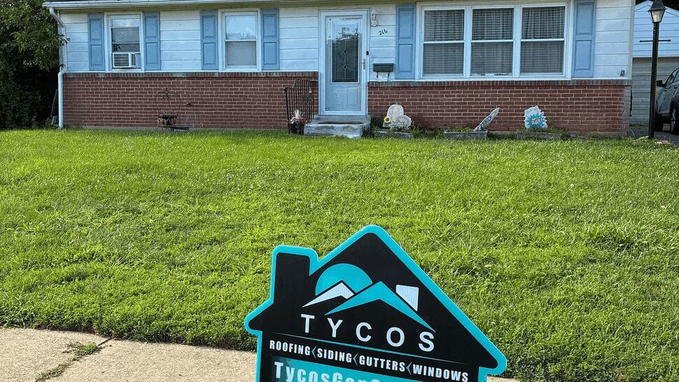 Ranch home with solar panels | Tycos Roofing And Siding Inc Front of a ranch house with solar panels and a Tycos yard sign in the lawn