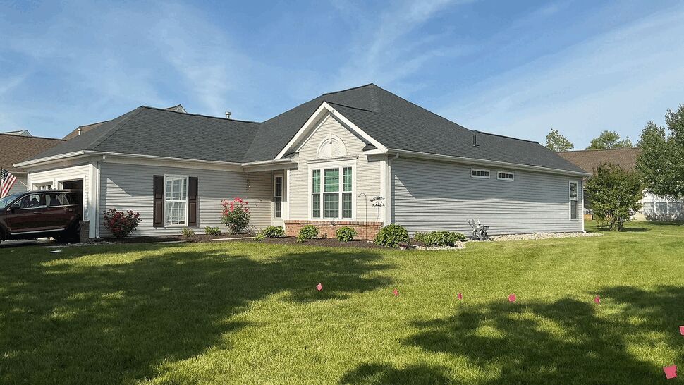 Ranch style home with gray roof and vinyl siding on a sunny day