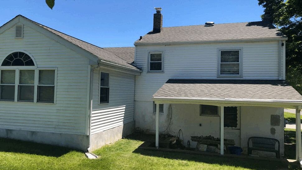 Rear of house with covered porch, white siding and shingled roof