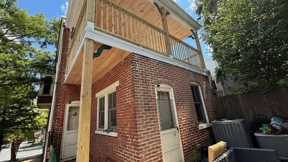 Renovated rear deck and entryway at a brick residence with new posts.