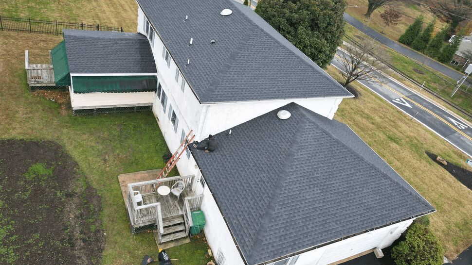 Overhead shot of rear deck, ladder, and technicians working on the roof.
