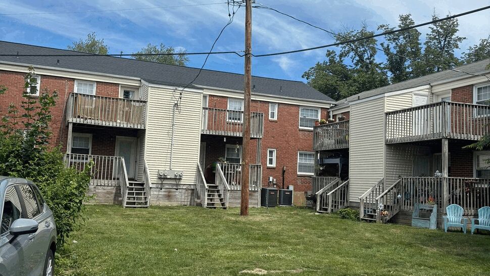 Rear view of multiunit building showing wooden decks, siding, and parking area.