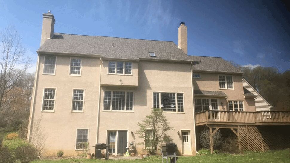 Rear elevation of a large house with an elevated wooden deck and multiple windows