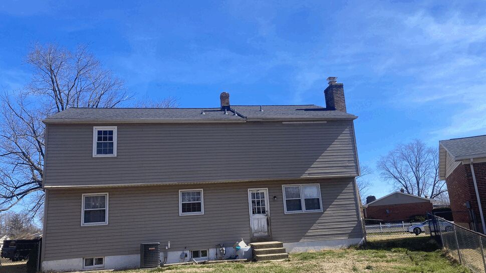Rear view of house showing siding, windows, and roofline with backyard