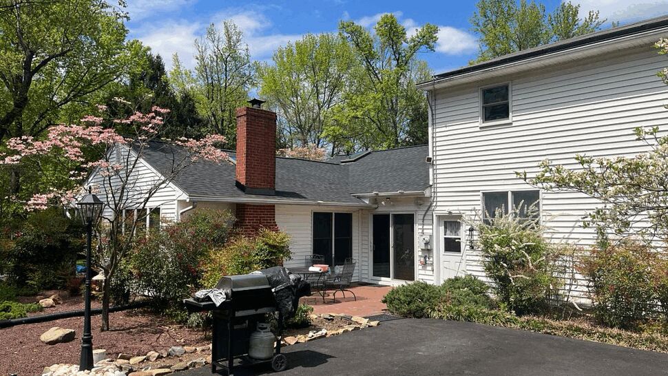 Rear patio with grill, brick chimney and visible gutters along the roofline