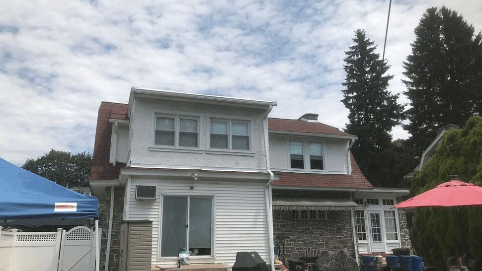 Backyard view with white siding, sliding patio door, and red roof