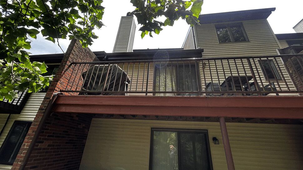 Rear two-level deck with metal railing, sliding door and brick chimney.