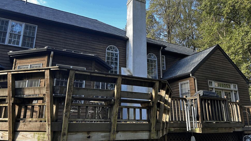 Weathered wooden back deck with railing attached to house and chimney