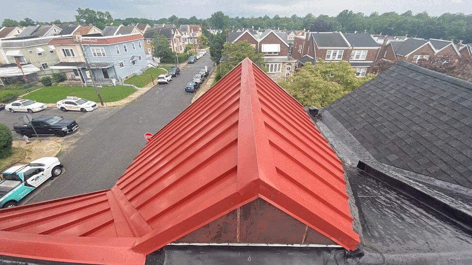 Ridge View of Red Metal Roof | Tycos Roofing And Siding Inc High-angle view down a red standing-seam ridge overlooking a neighborhood street