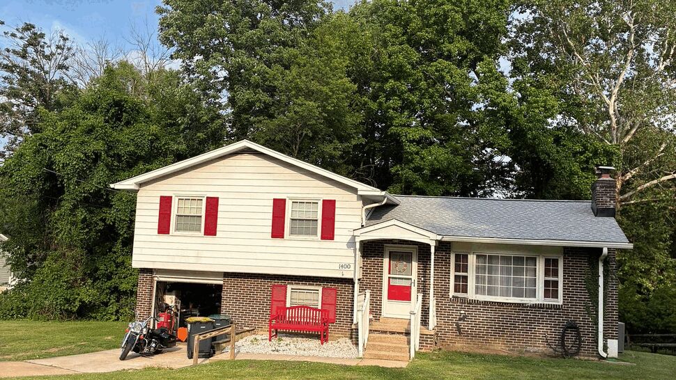 Front view of split-level home with red shutters and gray roof