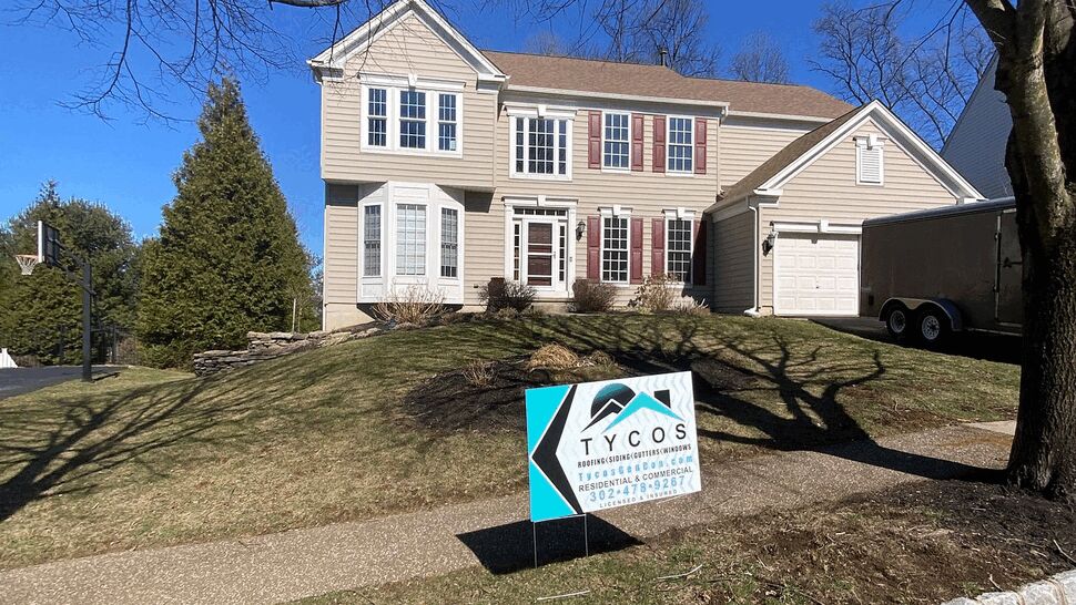 Two-story beige house with a Tycos sign on the front lawn.