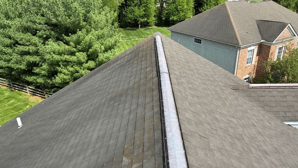 Aerial view down a long roof ridge with a ridge cap and surrounding homes