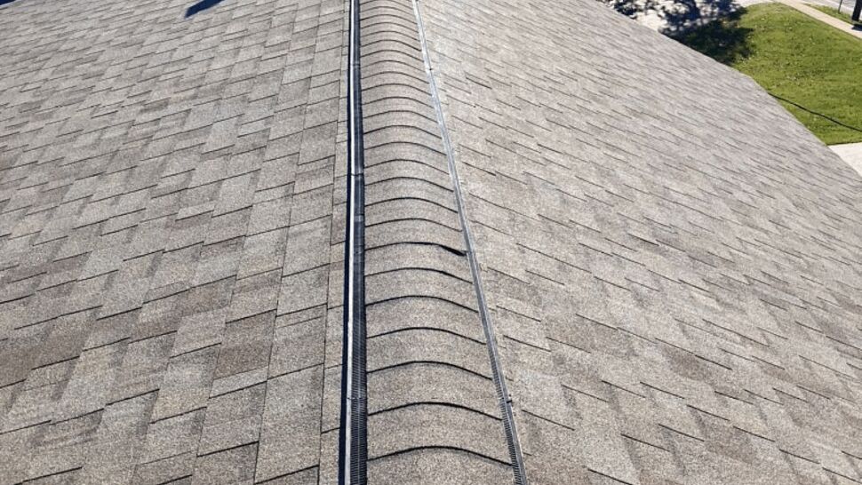 View along roof ridge showing installed ridge vent and asphalt shingles.