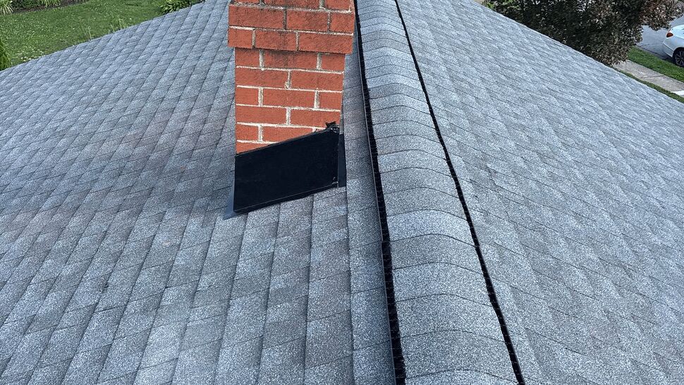 New shingle roof with chimney | Tycos Roofing And Siding Inc Gray asphalt shingles around a brick chimney with ridge vent