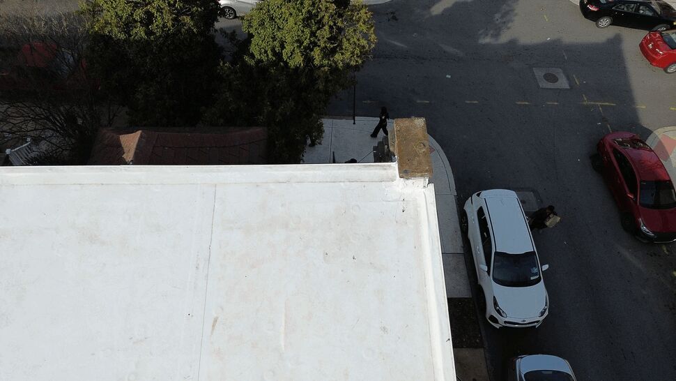 Flat roof corner and gutter edge view | Tycos Roofing And Siding Inc Overhead view of a roof corner and parapet edge overlooking the street