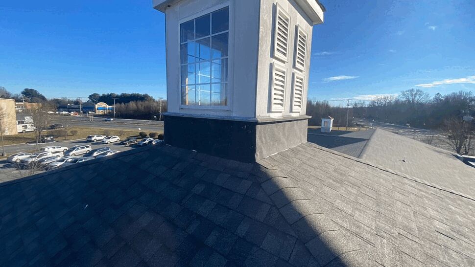 Close-up of roof cupola with window and asphalt shingles