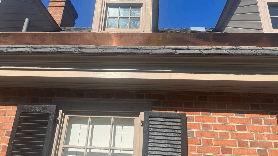 Shingle roof and dormer seen from below with clear blue sky