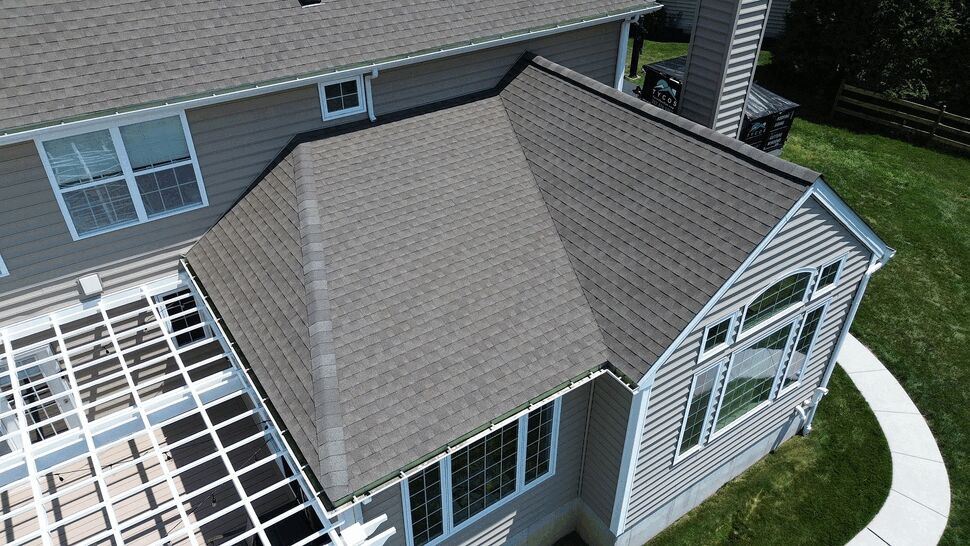 Close aerial of roof corner showing gutters, shingles and large windows